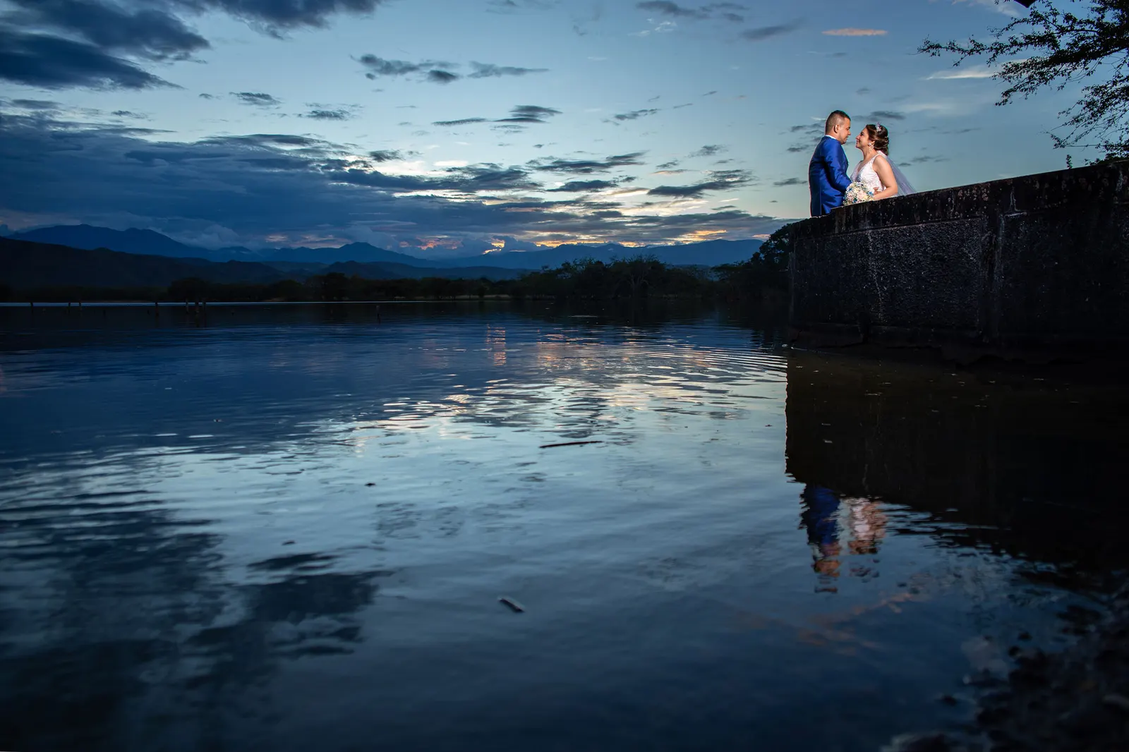 Pareja de novios reflejada en el agua al anochecer