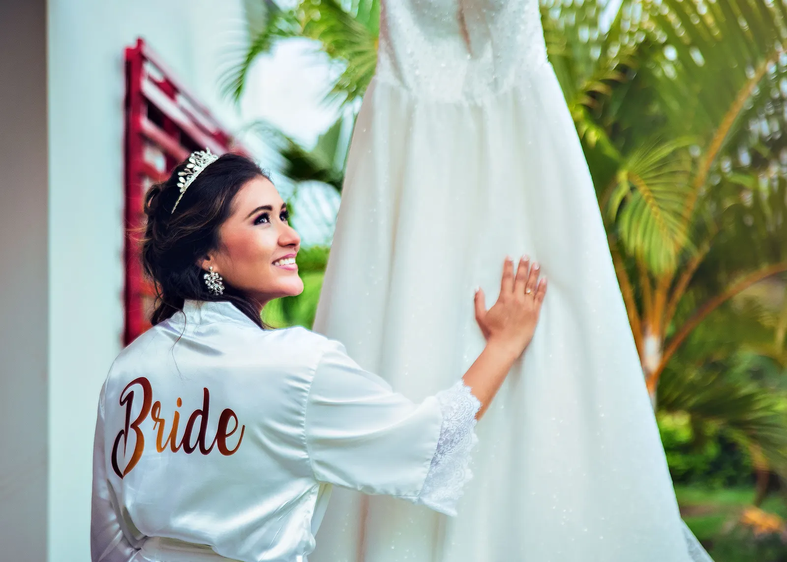 Novia sonriendo junto a su vestido, preparativos de boda