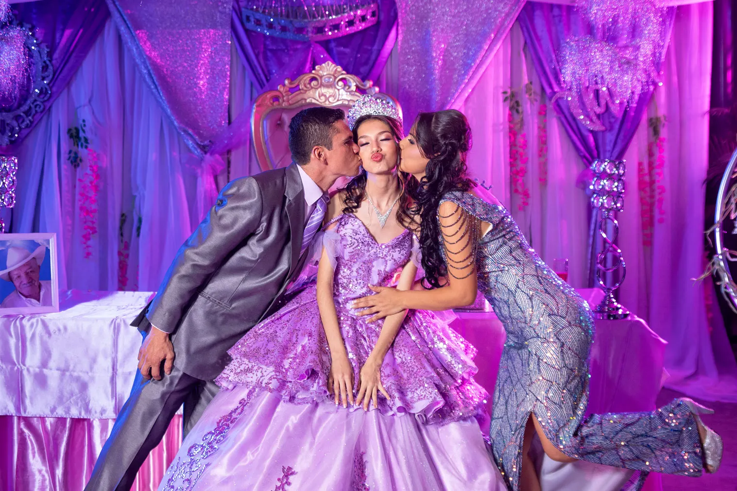 Quinceañera de lila recibiendo besos de sus padres