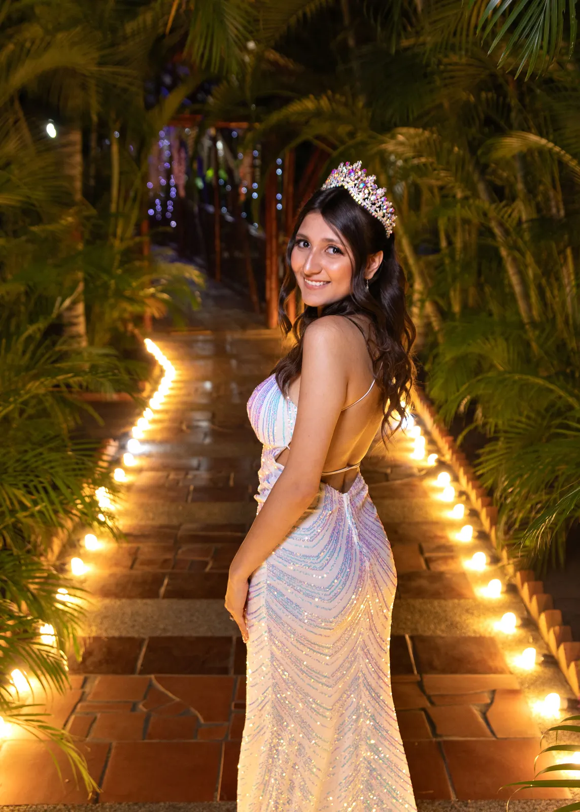 Quinceañera con vestido de lentejuelas en un sendero iluminado