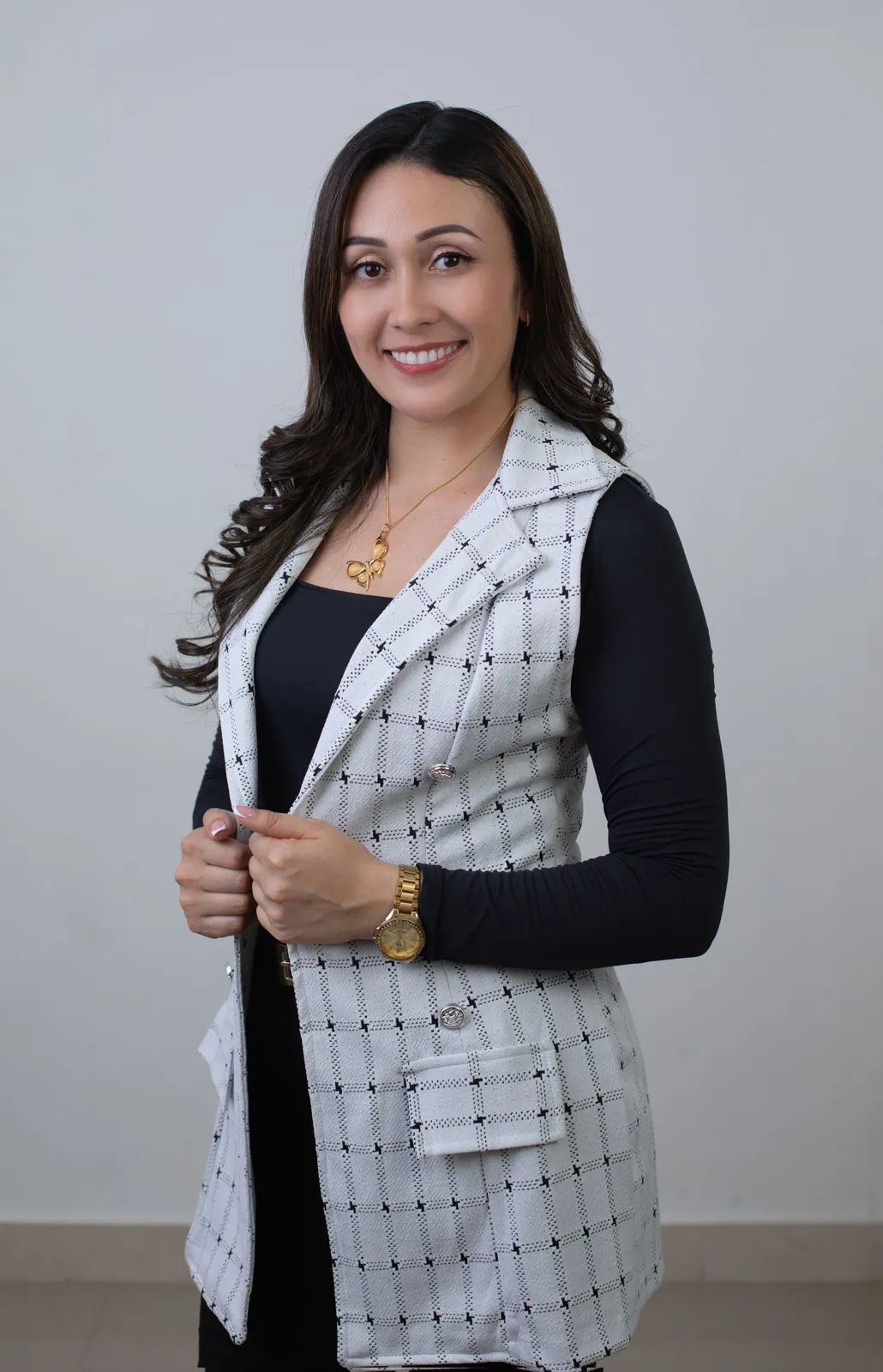 Retrato de marca personal con chaleco de cuadros y collar de mariposa sonriendo