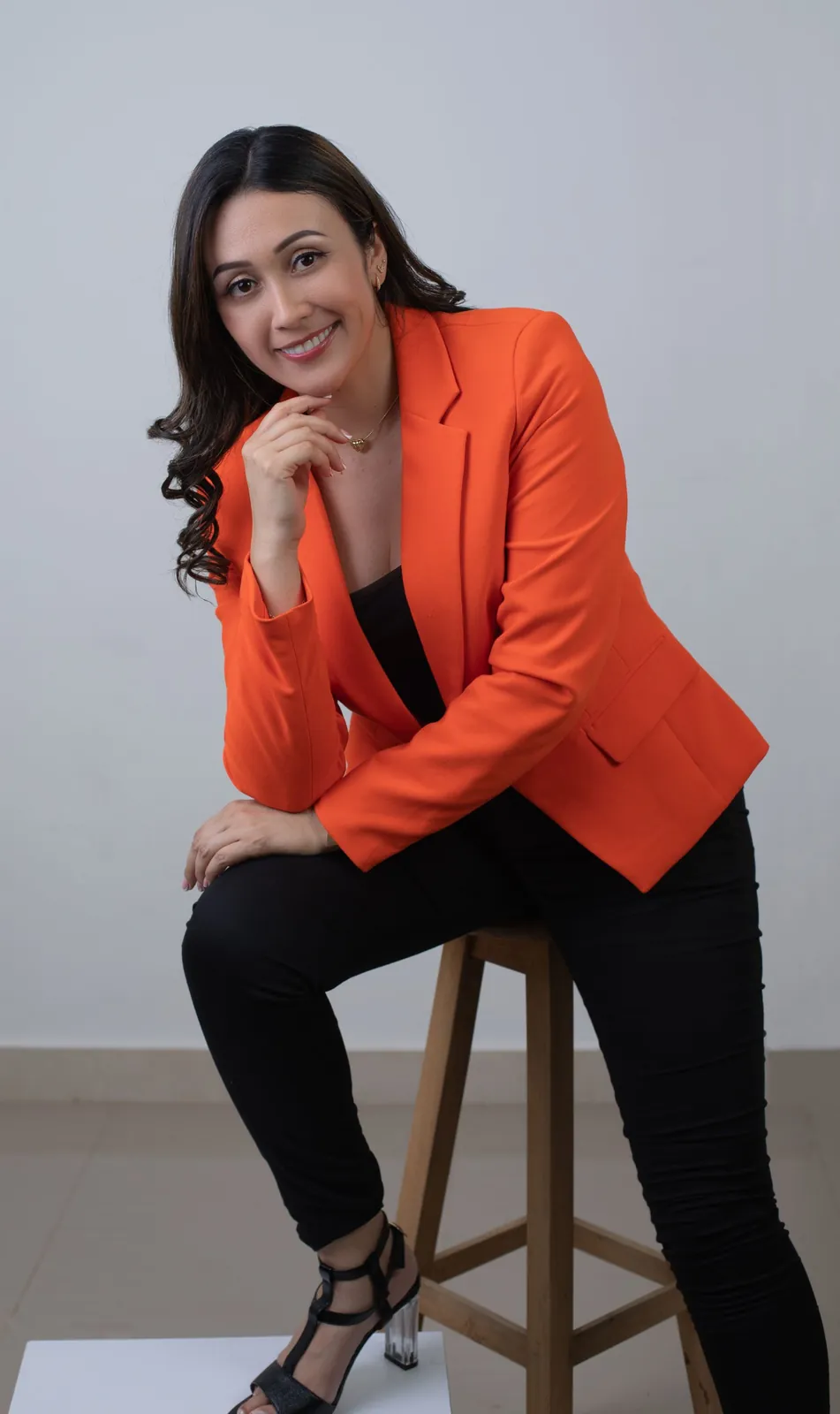 Retrato de marca personal con blazer naranja sentada en un banco sonriendo