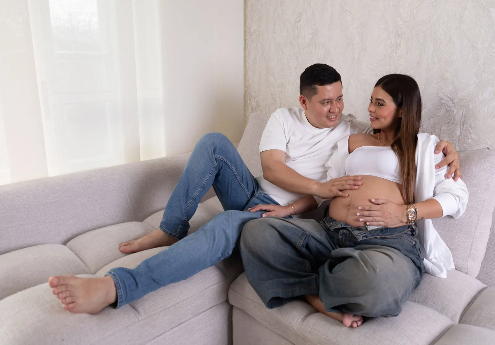 Futuros padres acariciando el vientre en una sesión de maternidad