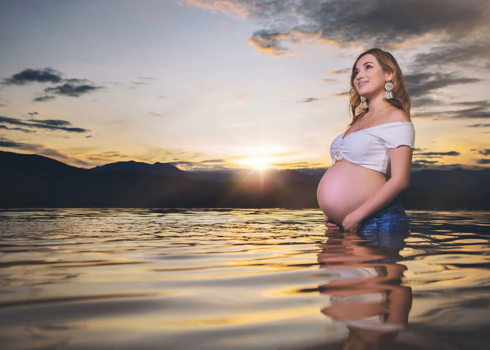 Mujer embarazada dentro del agua al atardecer