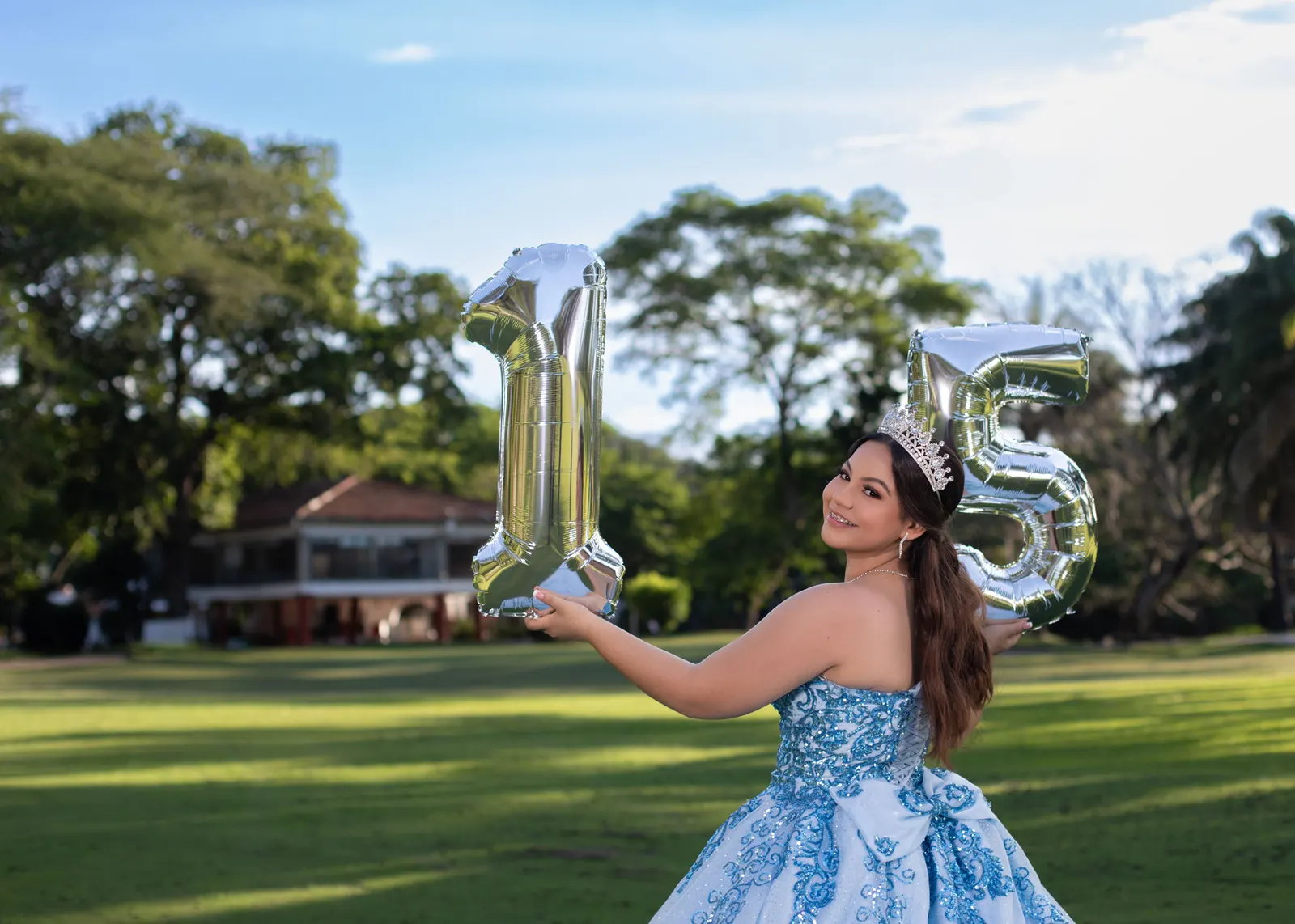 Quinceañera de vestido azul con globos plateados 15