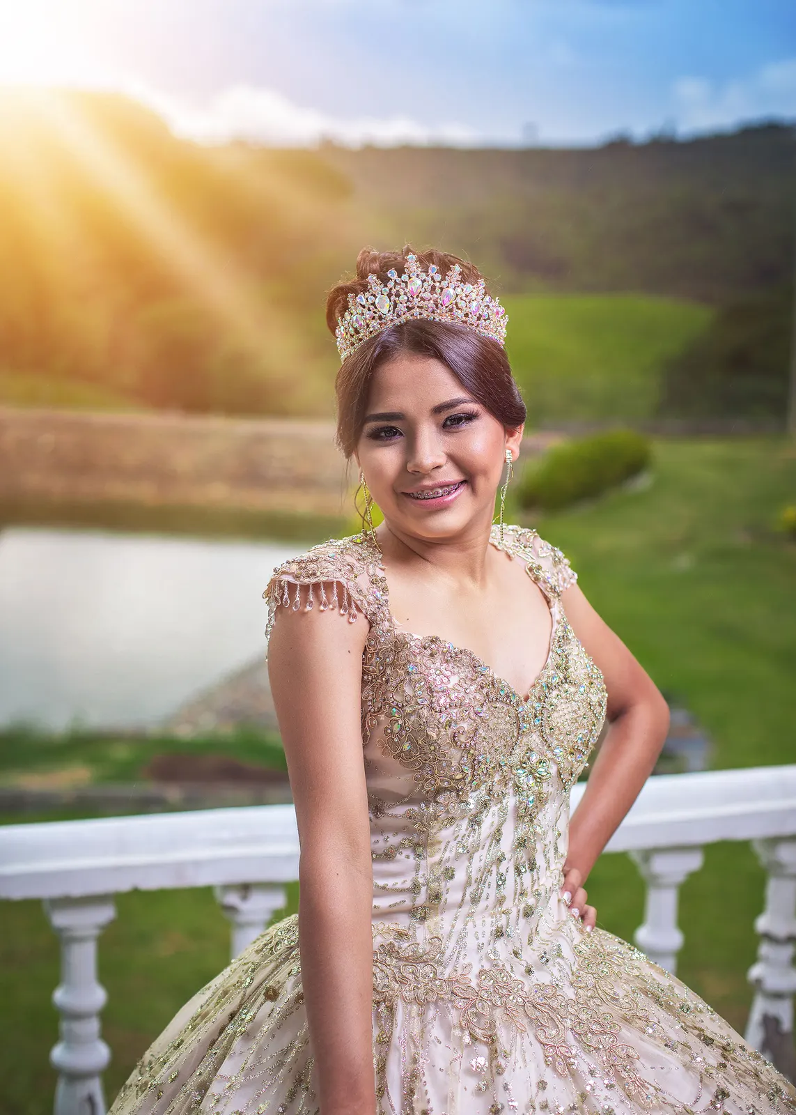 Retrato de quinceañera con vestido dorado y corona al atardecer