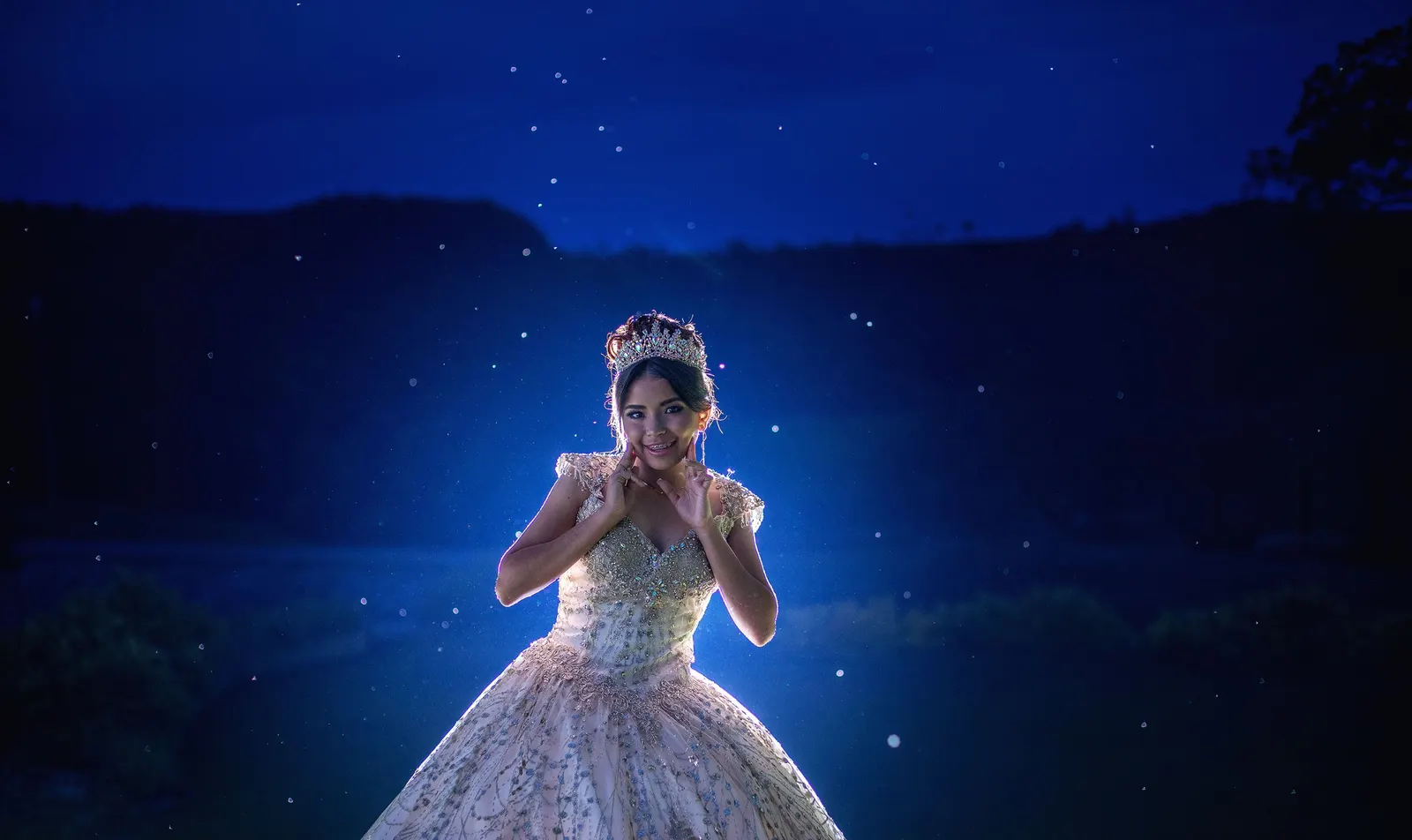 Quinceañera con vestido dorado bajo luz azul de noche