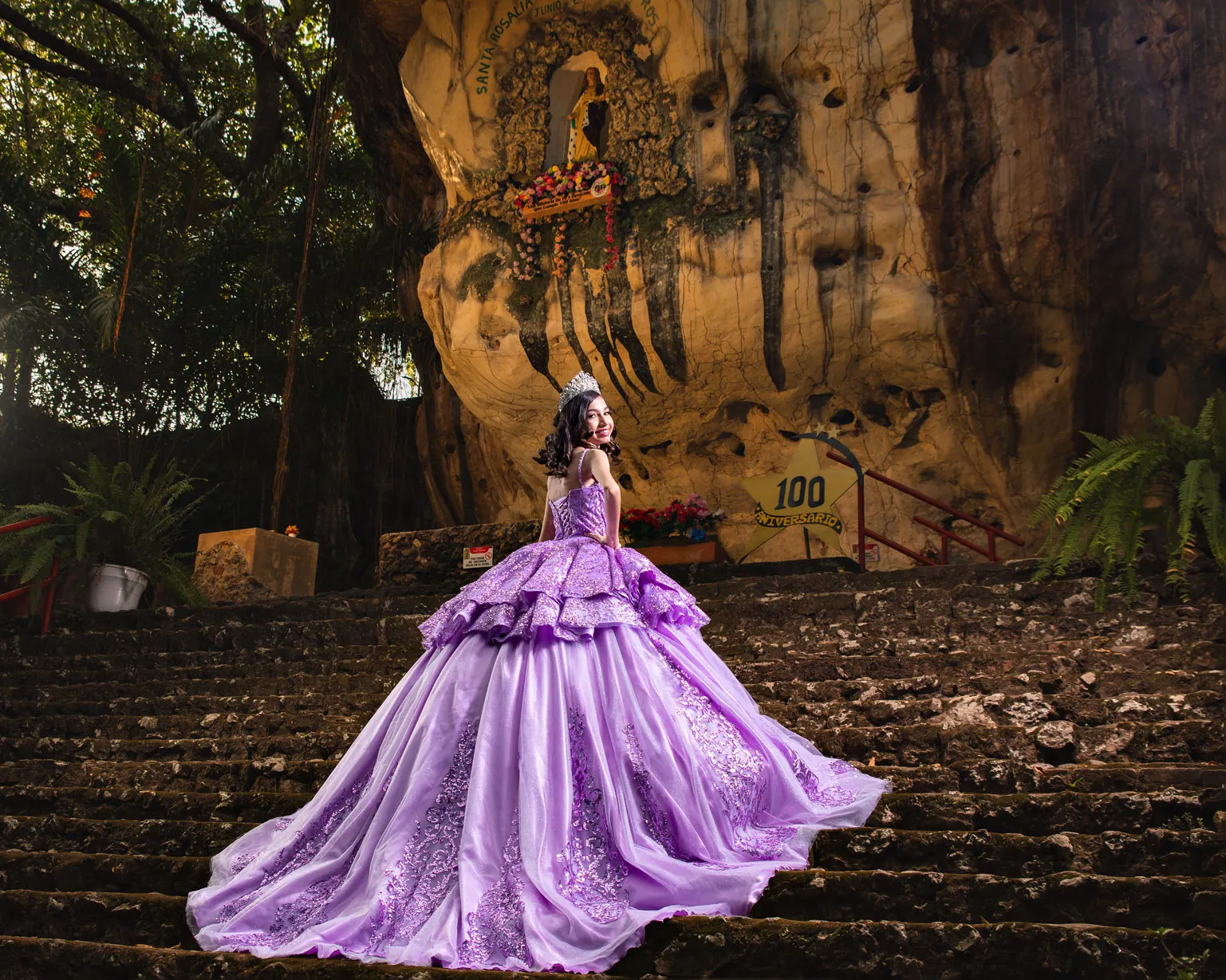 Quinceañera con vestido lila subiendo una escalinata de piedra