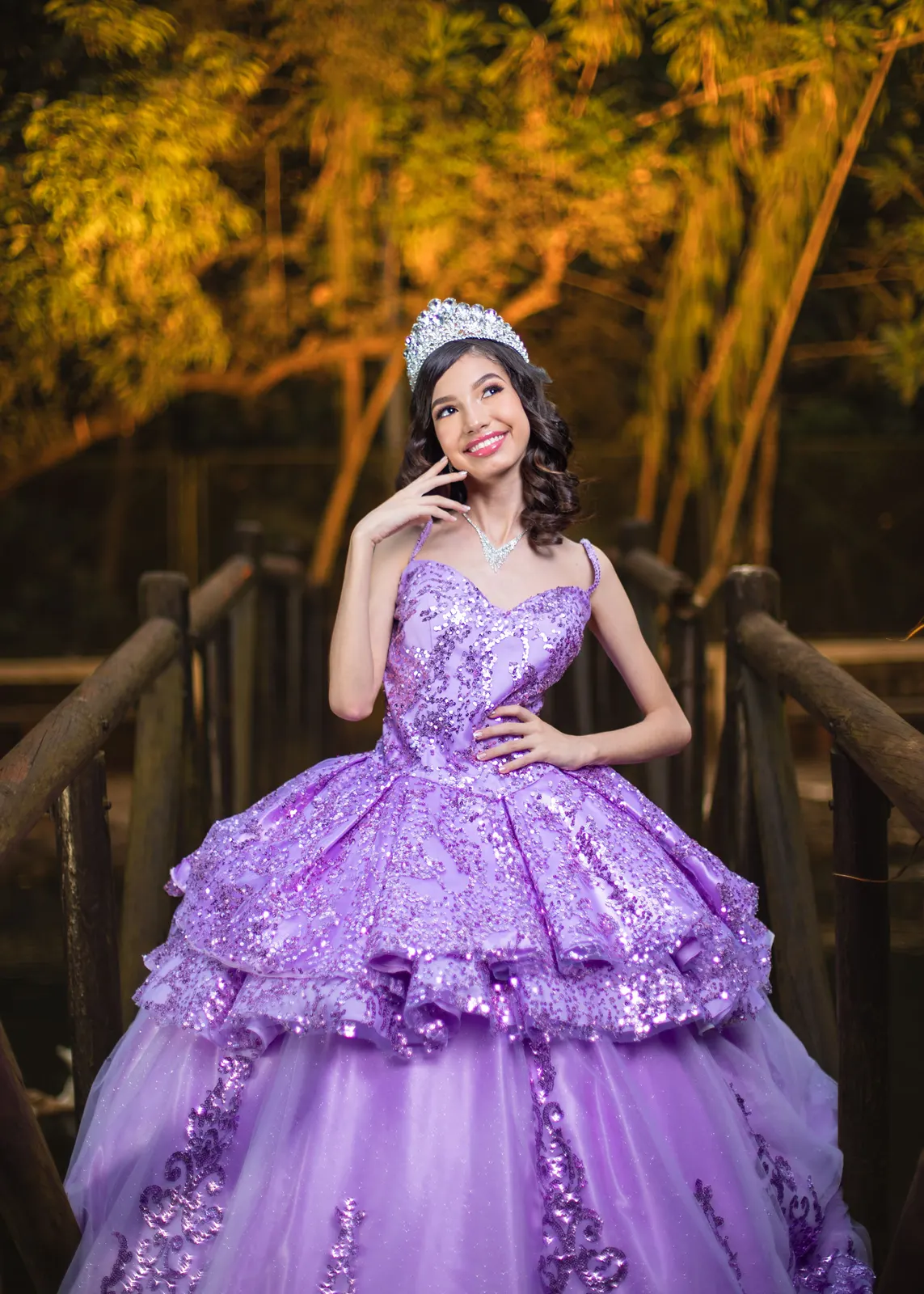 Quinceañera con vestido lila en un puente de madera