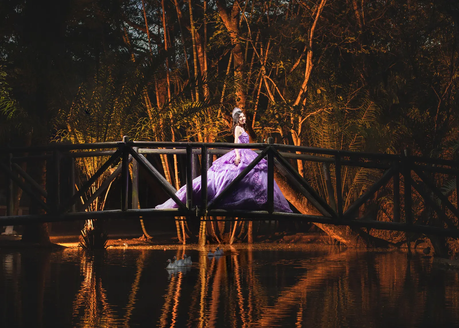 Quinceañera de lila sobre un puente junto a un estanque
